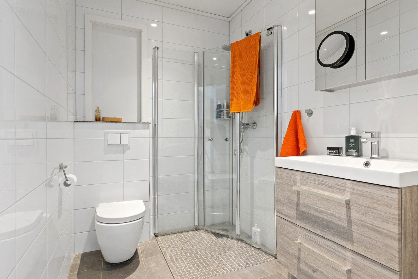 Begge badene er lyse og moderne, med fliser på gulv og varmekabler for ekstra komfort. Galleribilde