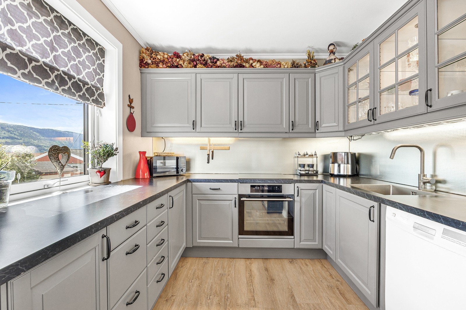 Kjøkkenet har malte profilerte fronter, laminat benkeplate og integrerte hvitevarer som medfølger. Plass til kjøleskap i hjørnet. Galleribilde