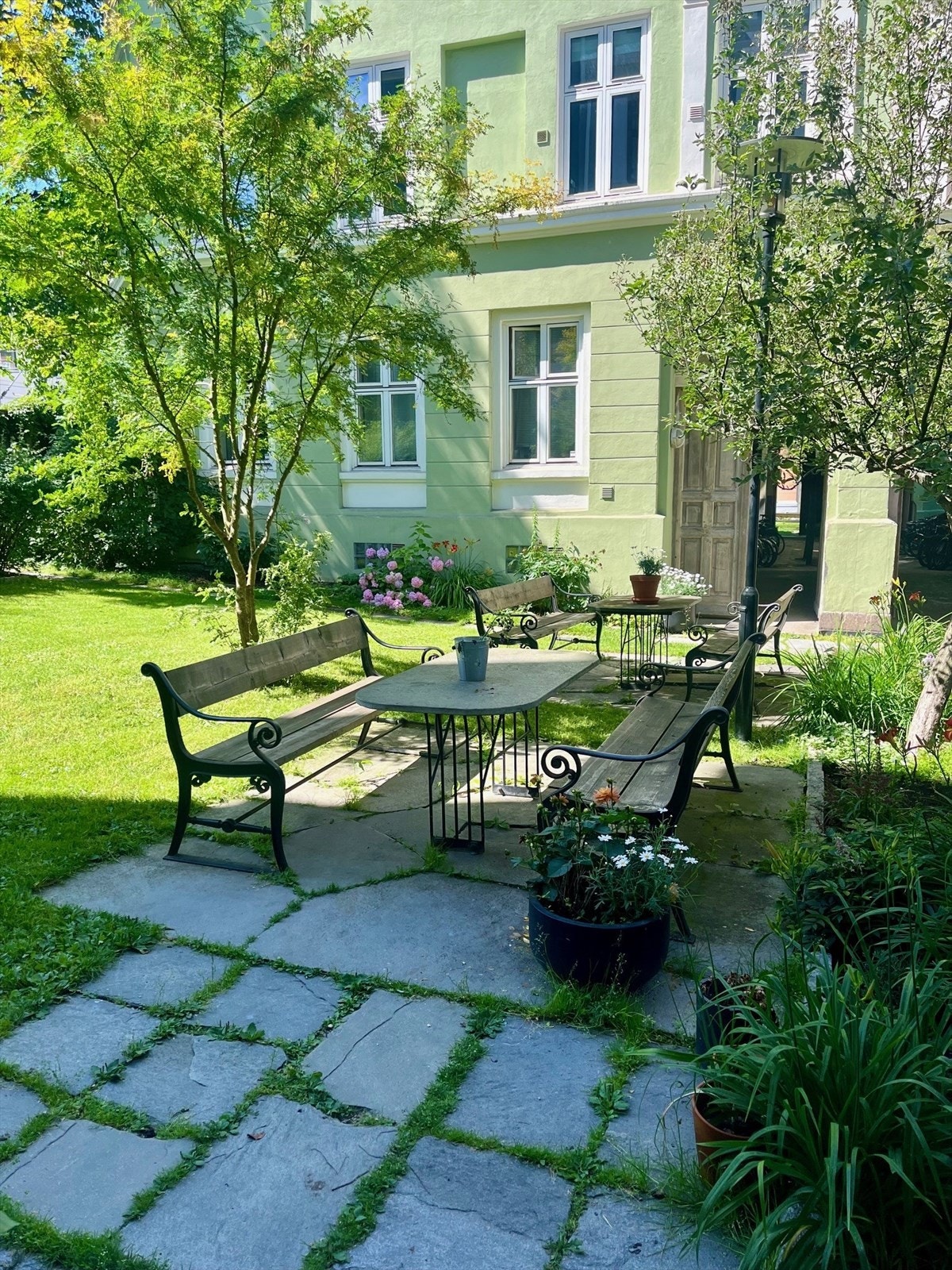 Bakgården er grønn og frodig på sommerstid, med plen, sittegrupper og diverse beplantning. Galleribilde