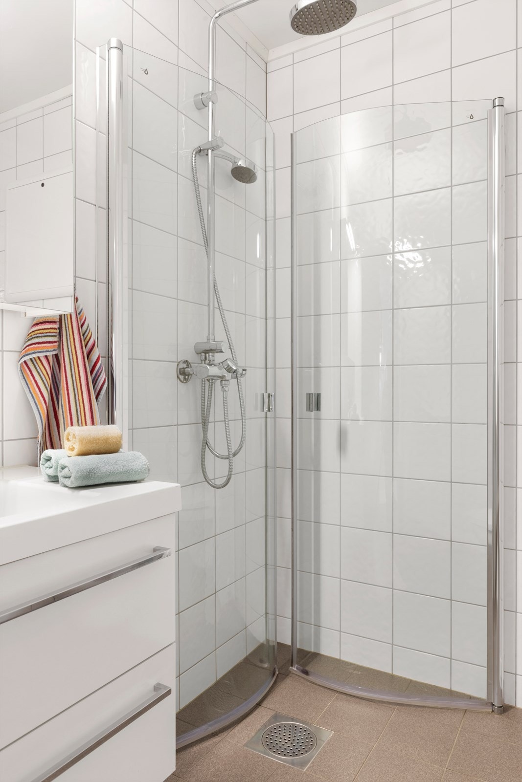 Badet har malt tak, flislagte vegger og gulv, samt baderomsinnredning med vegghengt WC og dusjvegger. Galleribilde