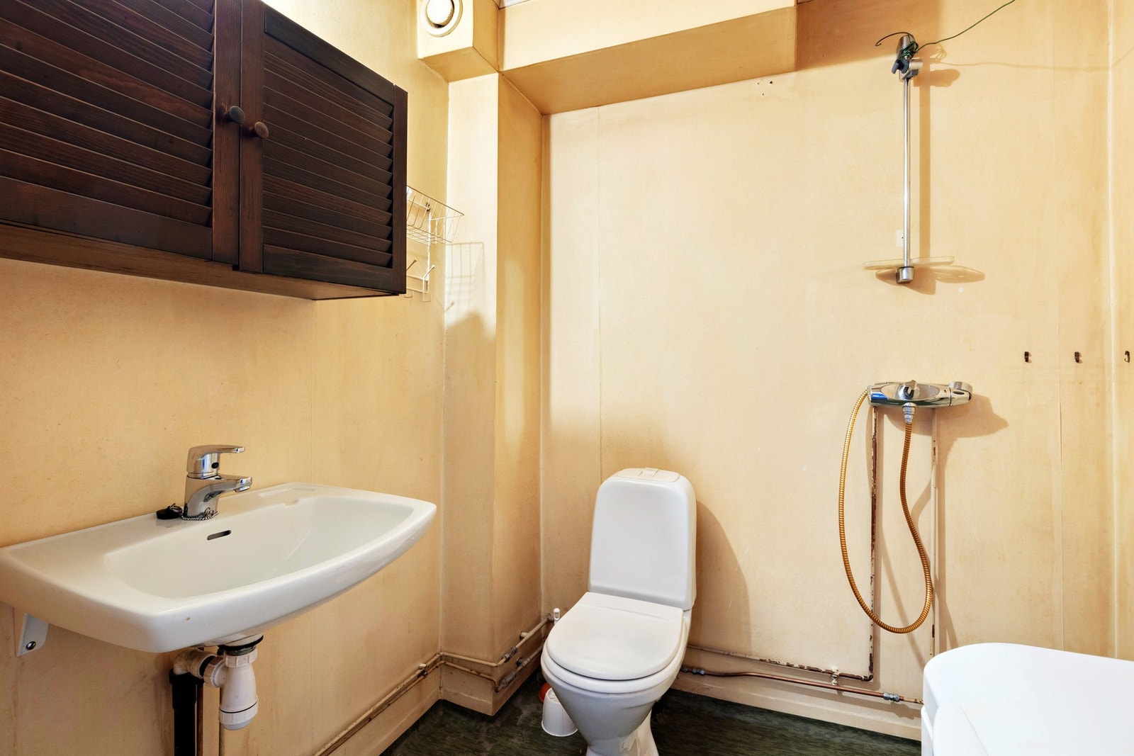 Badet er innredet med dusj, gulvstående wc, servant, belysning og opplegg for vaskemaskin. Galleribilde