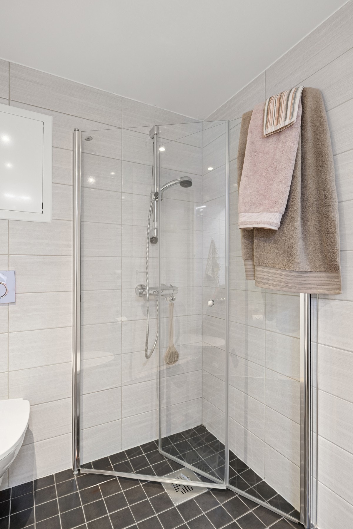 Baderom tilknyttet entré med servant med underskap og speilskap, dusjhjørne med innfellbare glassdører i herdet glass, samt vegghengt toalett. Galleribilde