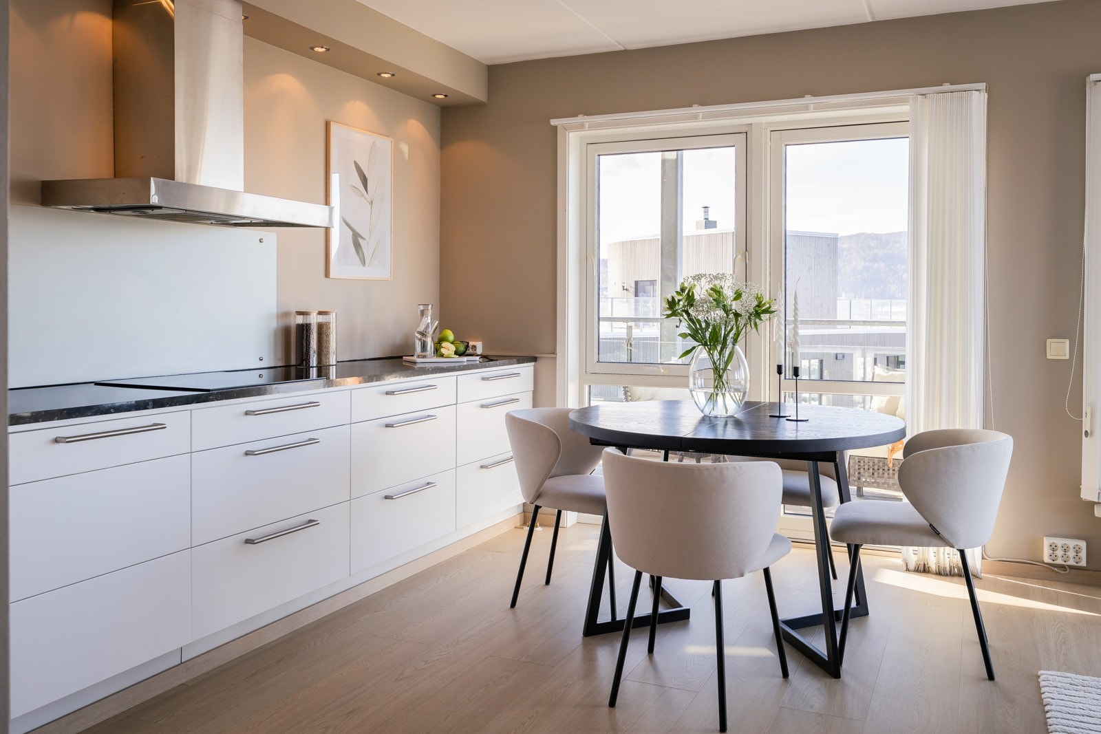 Stilren belysning fra downlights over den utstrakte benkeplata på kjøkkenet. Galleribilde