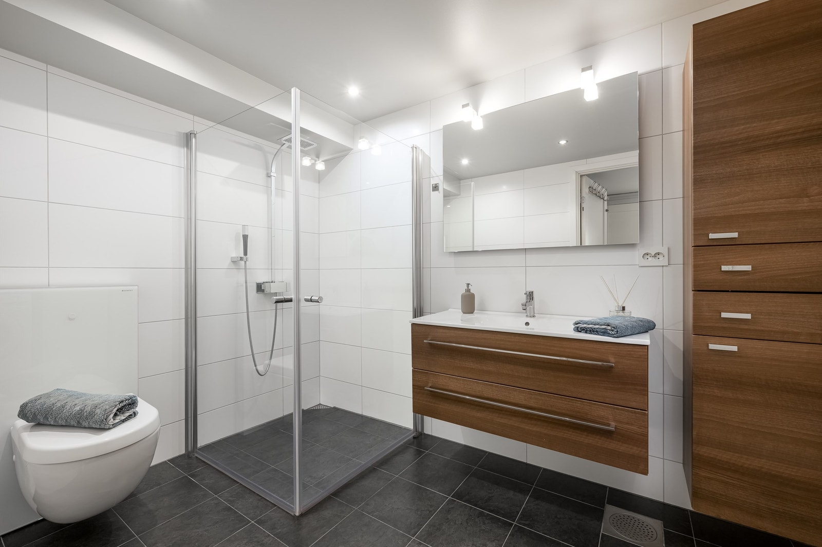 Badet, som er fra byggeåret, er helfliset og har dusjhjørne med dører, vegghengt servantinnredning, vegghengt baderomsmøbel og veggmontert toalett. Gulvvarme på gulv. Galleribilde