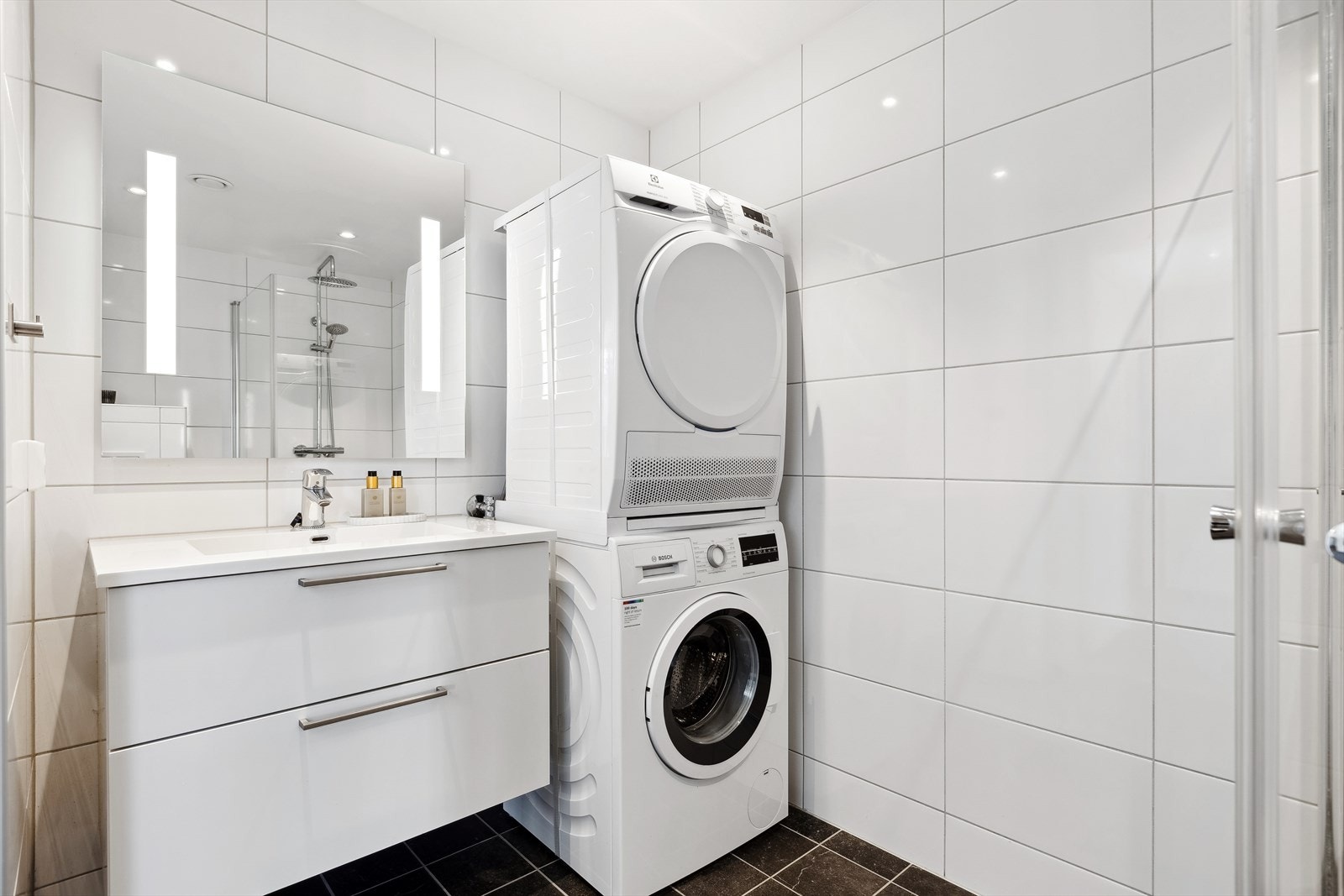 Badet er flislagt og har lun gulvvarme, stilren innredning og opplegg for vaskemaskin. Galleribilde