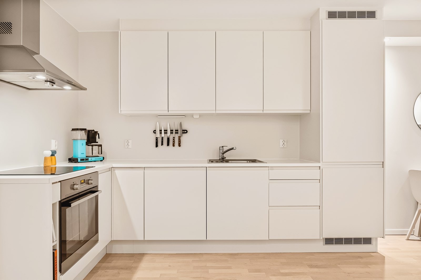 Kjøkkeninnredningen består av slette hvite fronter, laminat benkeplate med nedfelt vask og integrerte håndtak. Galleribilde