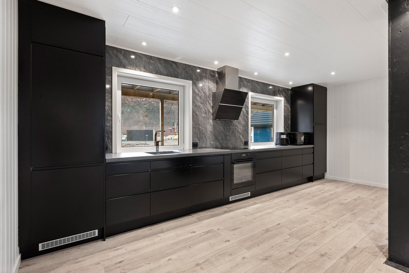 Kjøkken med kjøl/fryseskap, komfyr og induksjonstopp. Galleribilde