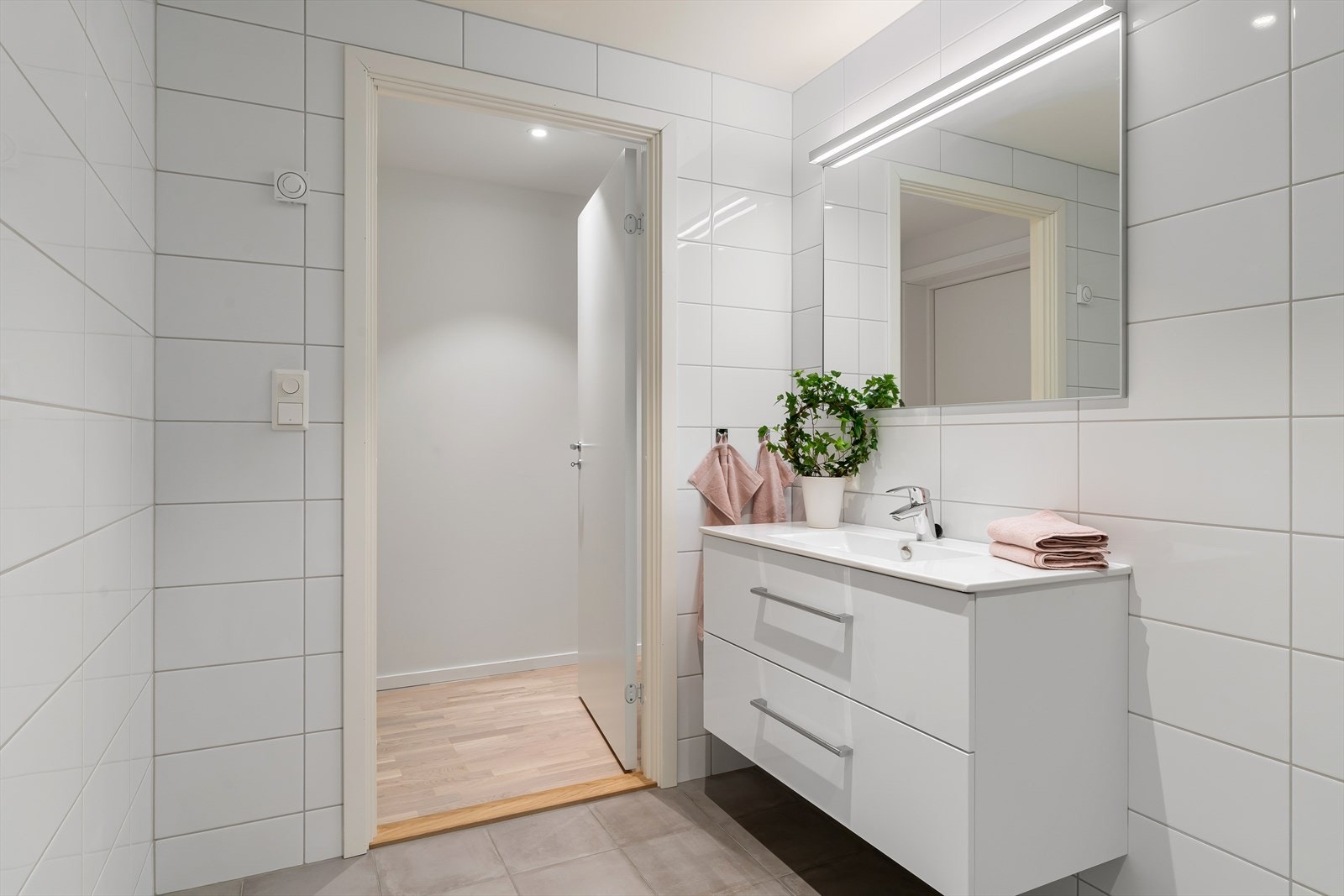 Badet er flislagt og er innredet med vegghengt toalett, servant i skuffeinnredning og dusjhjørne. Galleribilde