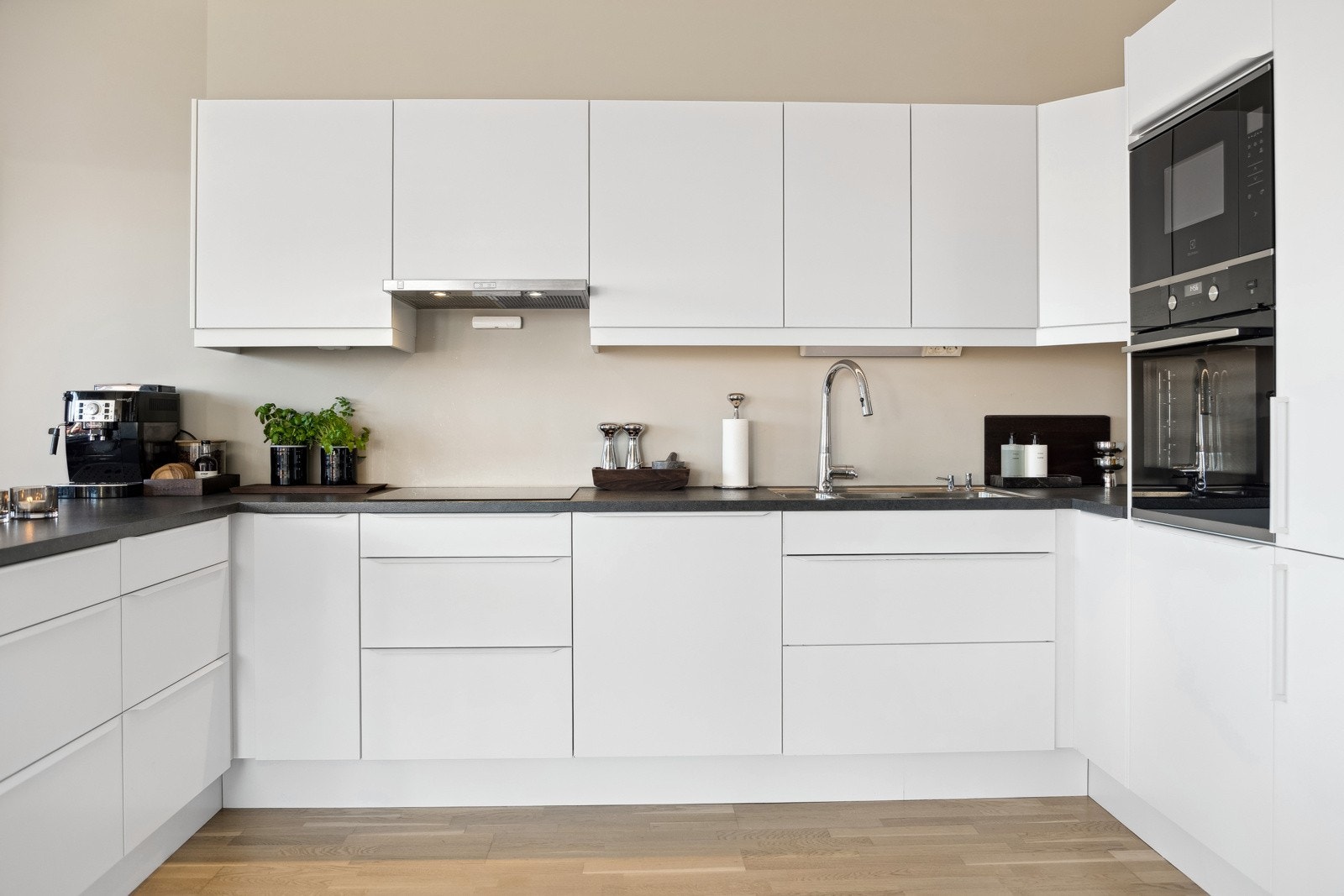 Lys og elegant kjøkkeninnredning fra Sigdal med integrerte hvitevarer som stekeovn, platetopp, oppvaskmaskin, mikrobølgeovn og kjøleskap med fryser. Galleribilde