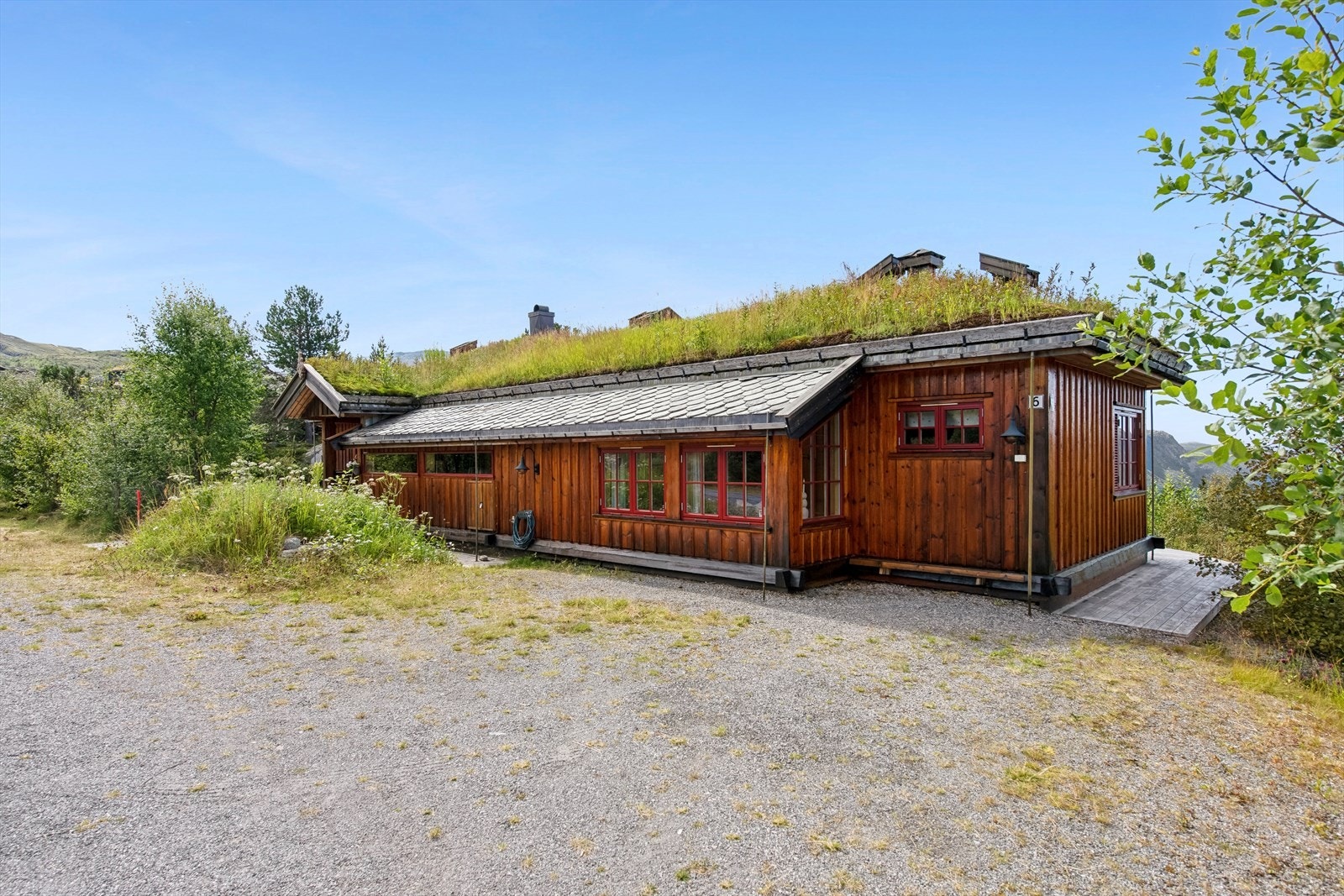 Den utvendige utformingen gjenspeiler boligens kvalitet og særegenhet. Taktekkingen består av en kombinasjon av torv og skiferstein, mens takrenner og nedløp er designet med påsatt trestokk, som tilfører et rustikt og naturnært uttrykk. Galleribilde
