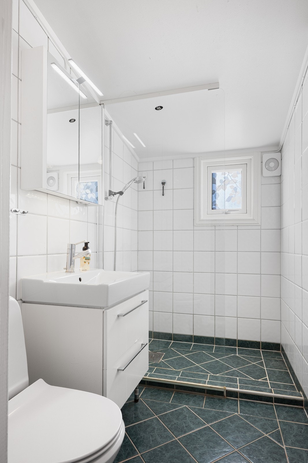 Badet fremstår tidløst med flislagte overflater, varmekabler og romslig dusjnisje med glassvegg. Galleribilde