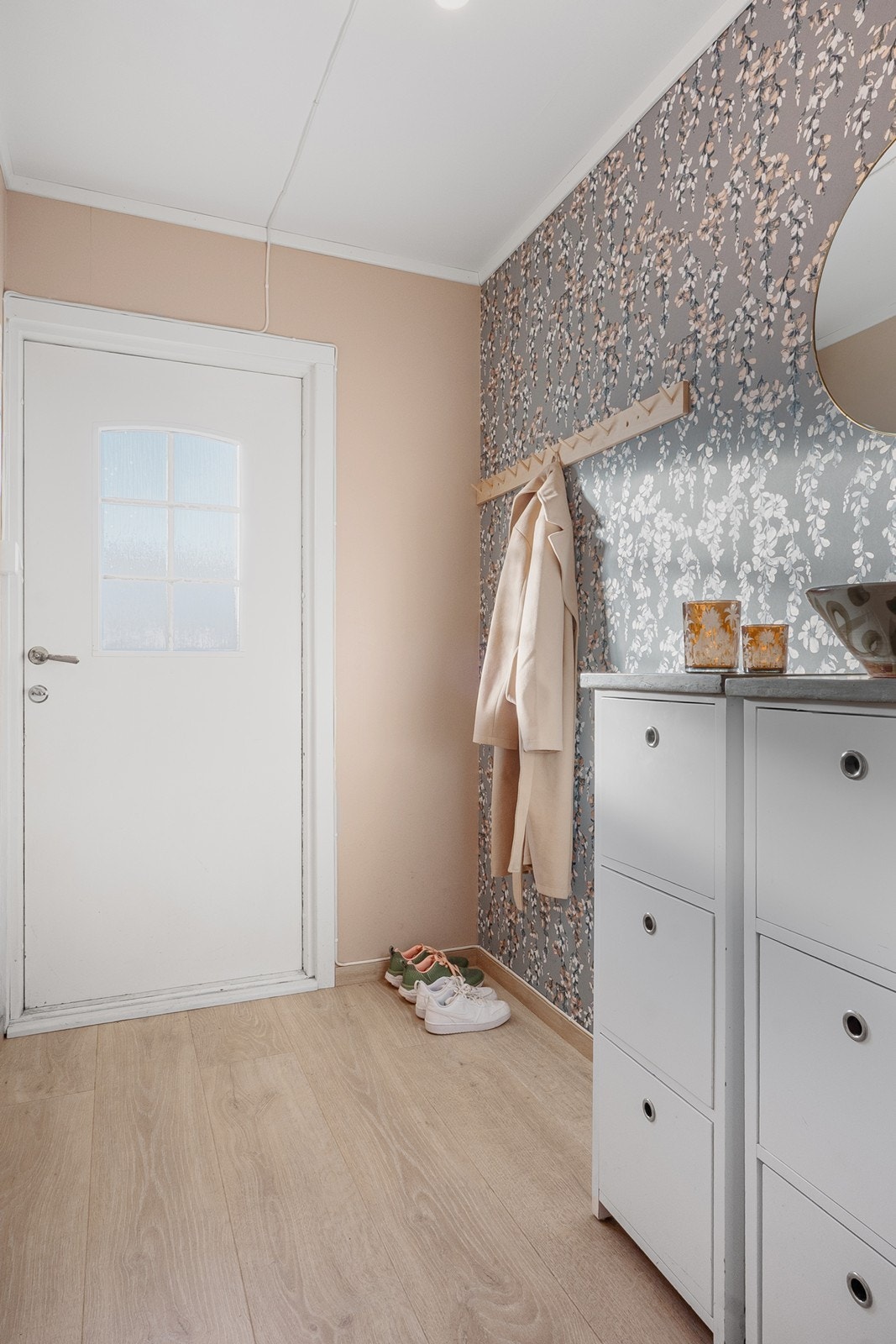 Vel inne fremstår entreen lys og innbydende med knaggrekke og plass til skoskap eller oppbevaringsmøbel. Galleribilde