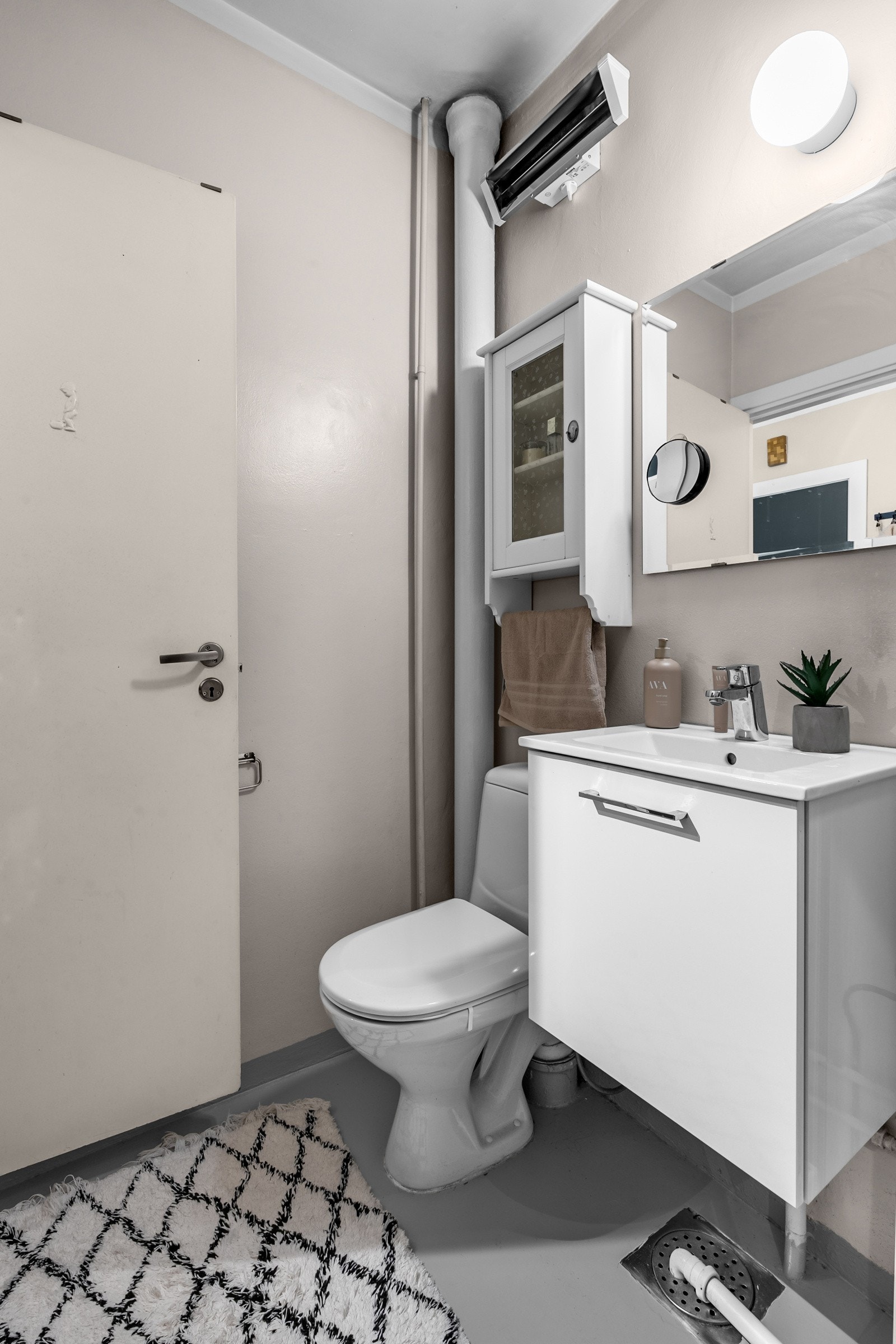 Badet er innredet med servantseksjon med skap, dusjkabinett, gulvmontert toalett og speil. Galleribilde