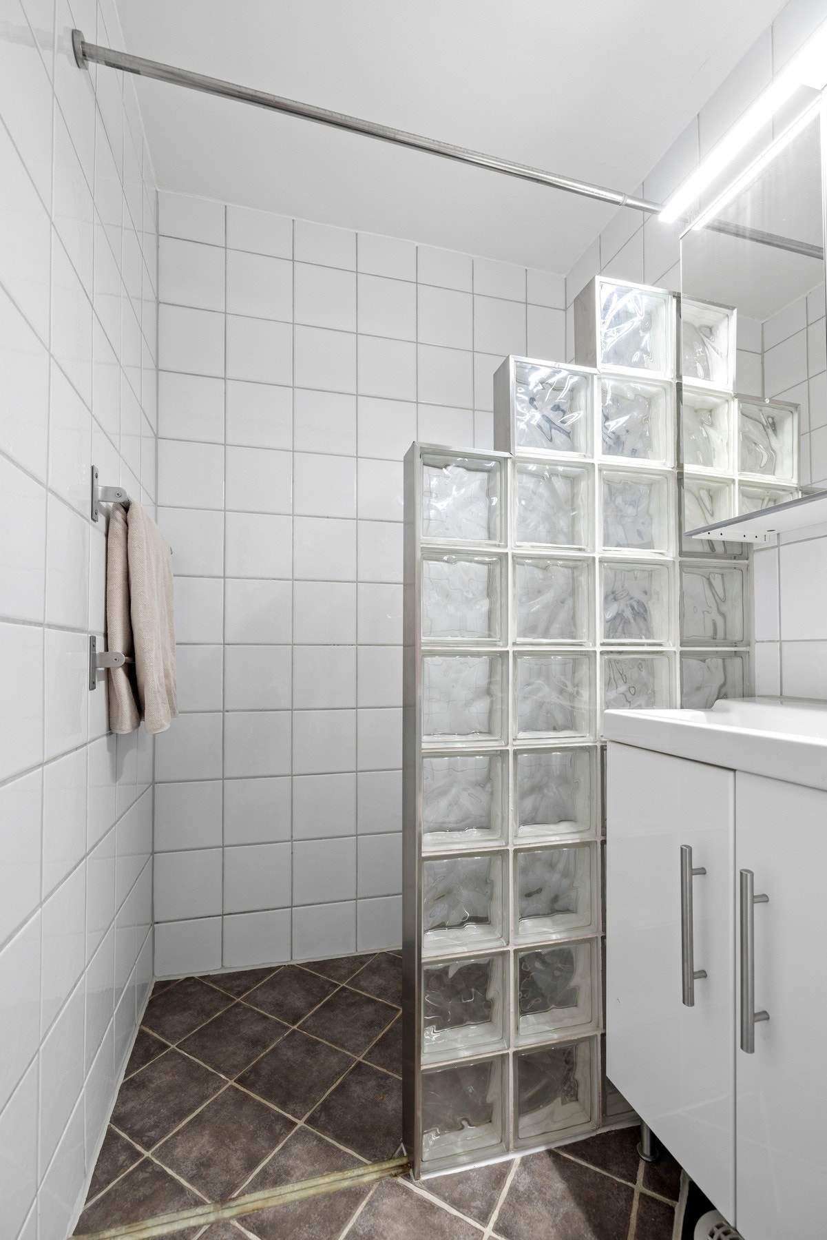 Bad med flislagte overflater og dusjvegg utført i glassbyggerstein Galleribilde