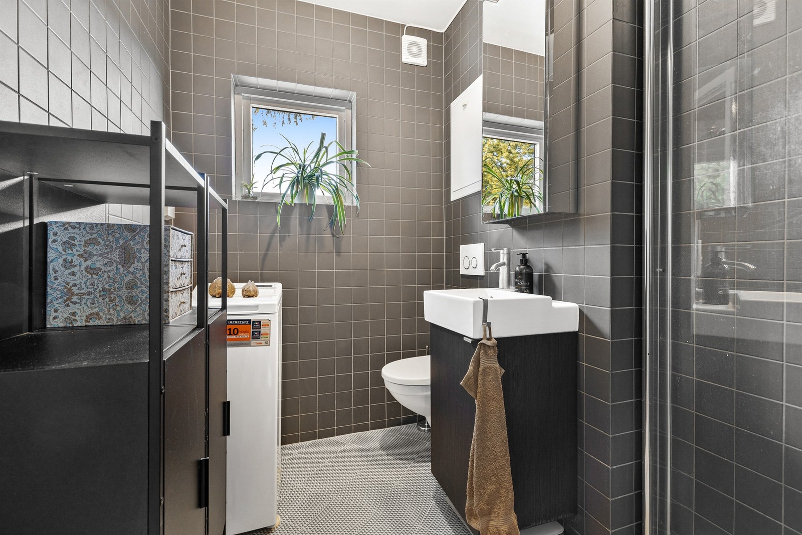 Rommet er innredet med vegghengt servantinnredning med ovenpåliggende servant, speilskap med overlys og vegghengt toalett Galleribilde