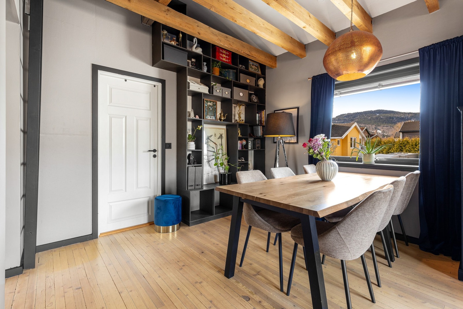 Stuen har en praktisk, plassbygd hylleløsning med sorte plater Galleribilde