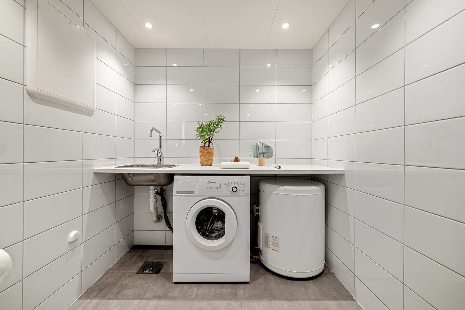 Vaskeromsdel med varmtvannstank, opplegg for vaskemaskin og benkeplate med nedfelt skyllekar. Galleribilde