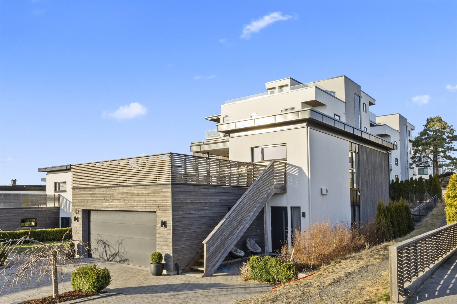 Tomten er pent opparbeidet med gressplen og beplantning av busker og trær i ulike soner på eiendommen. Galleribilde