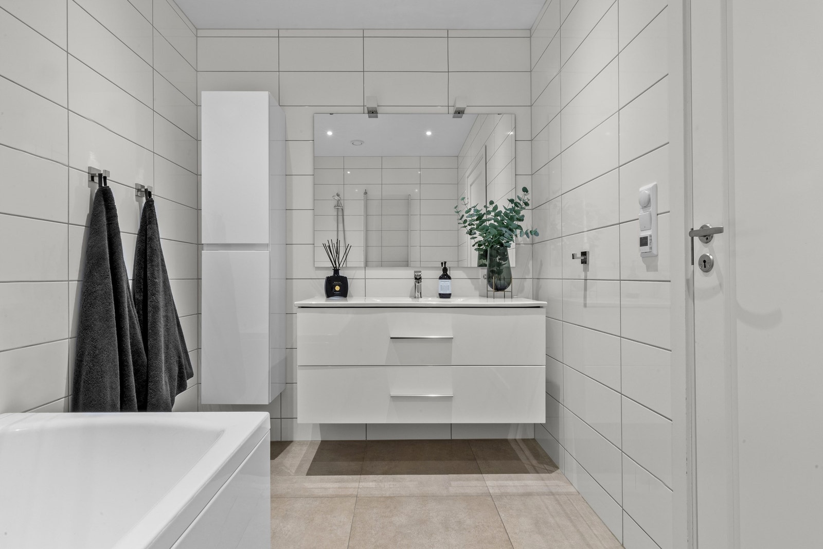 Pent baderom i 1. etasje med badekar, servant med innredning og vegghengt toalett. Rommet varmes opp med varmekabler. Galleribilde