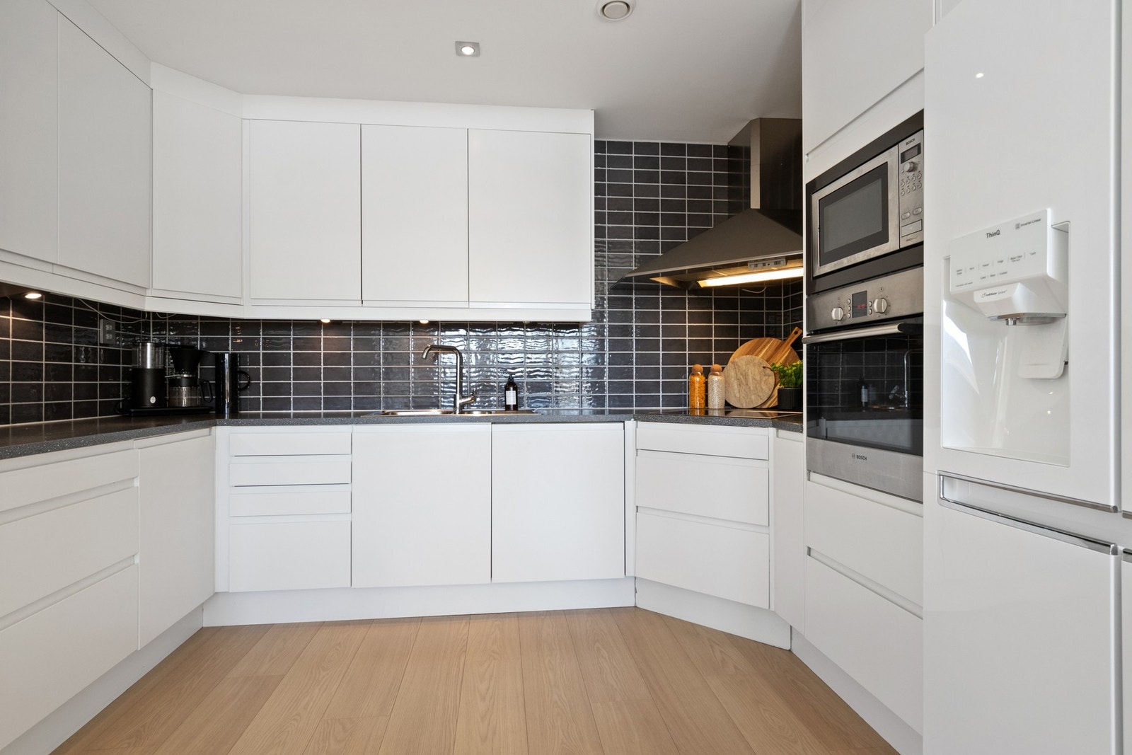 Innredningen har hvite, glatte fronter, takhøye skap og grå laminatbenkeplate med nedfelt kum i stål. Galleribilde