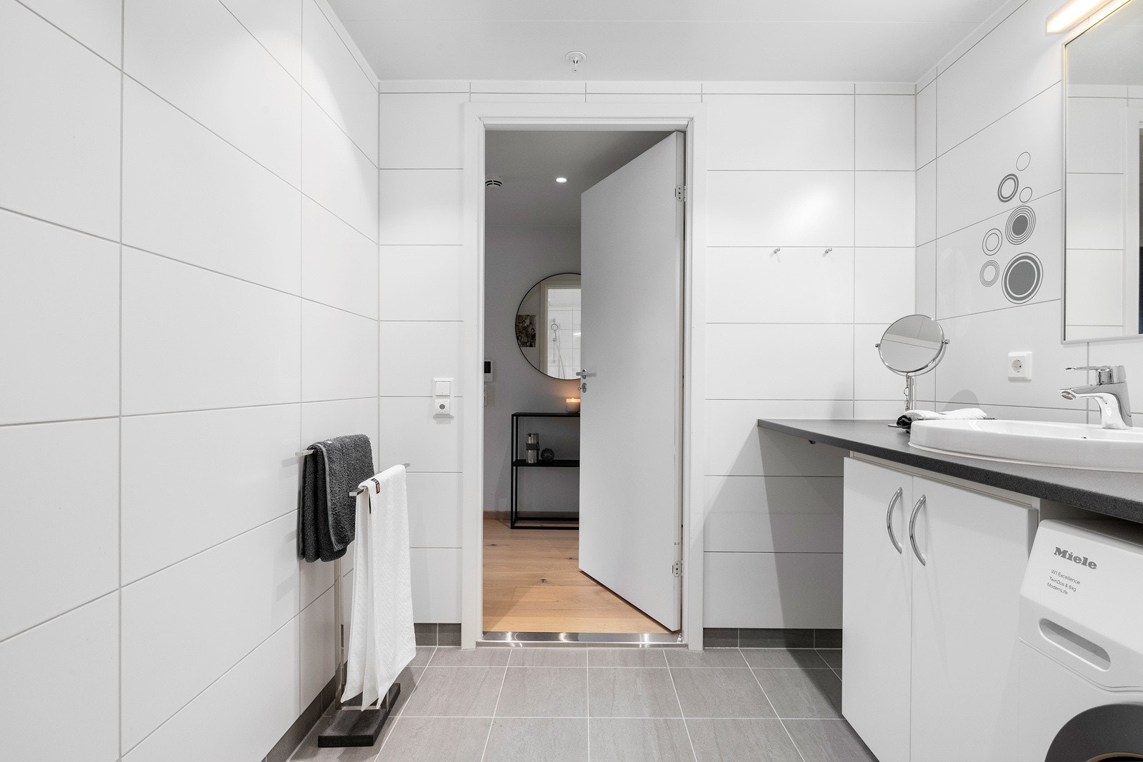 Rommet er innredet med vegghengt servantinnredning, veggehengt speil med lys, dusj på gulv og vegghengt toalett Galleribilde