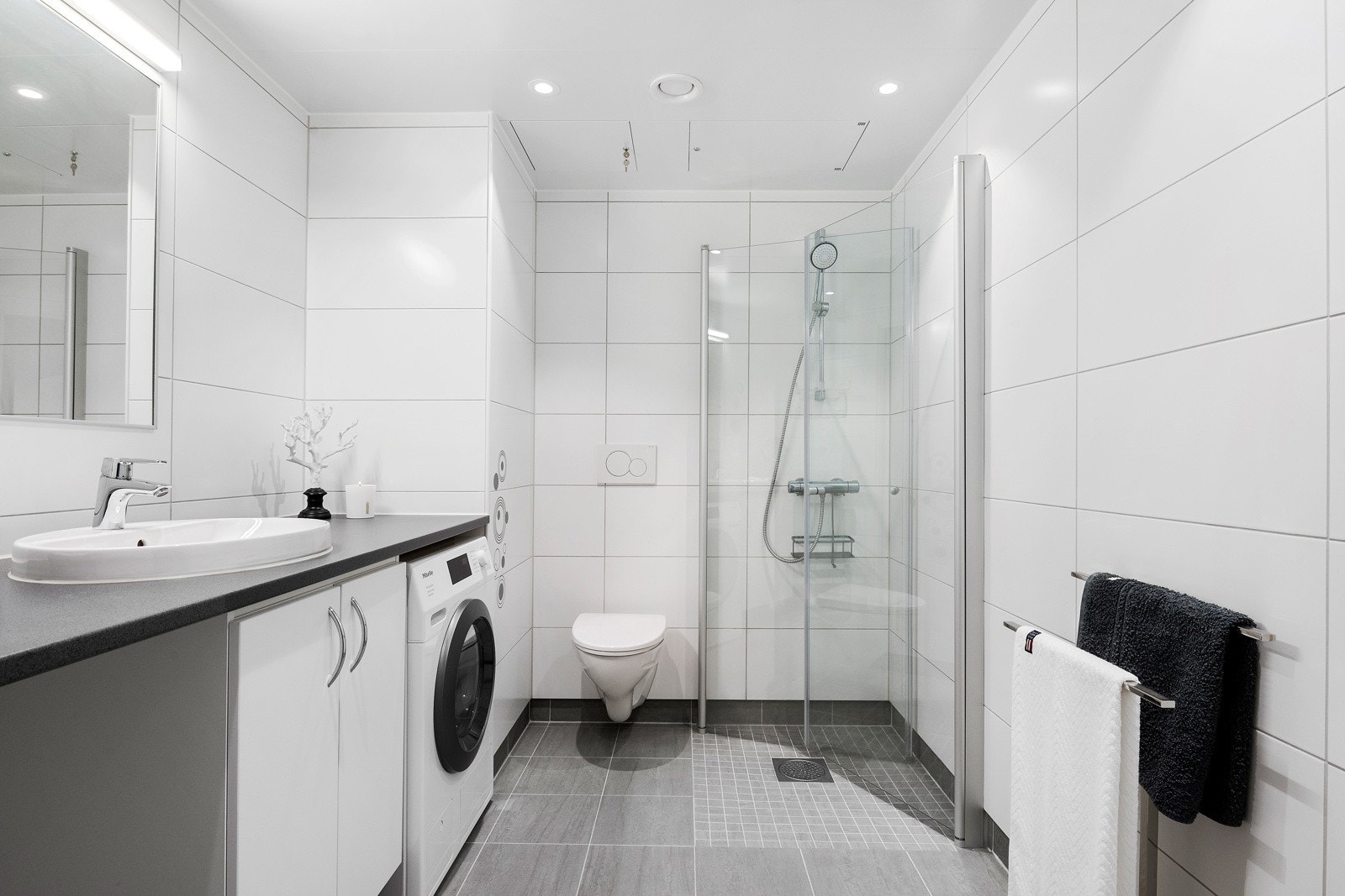 Moderne, helfliset baderom med varme i gulv, downlights i himling og opplegg for vaskemaskin Galleribilde