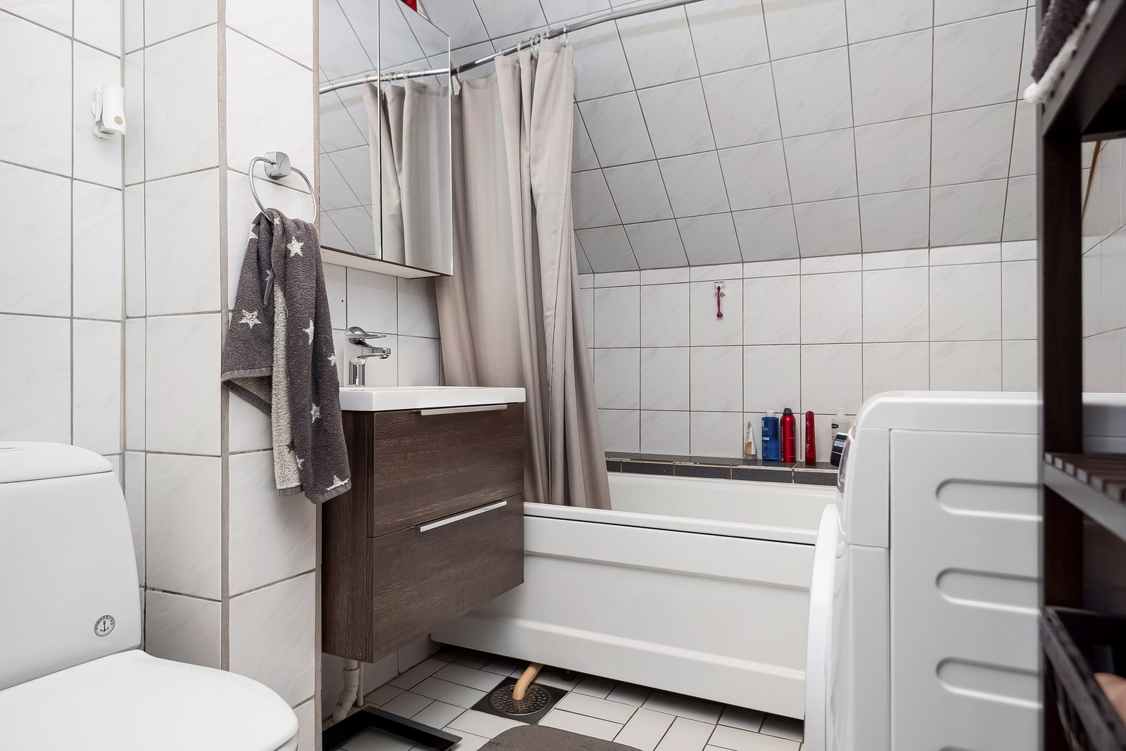 Badet på loftet er innredet med flislagte flater, varme i gulv, opplegg for vaskemaskin, badekar, toalett og servantskap med overskap. Galleribilde