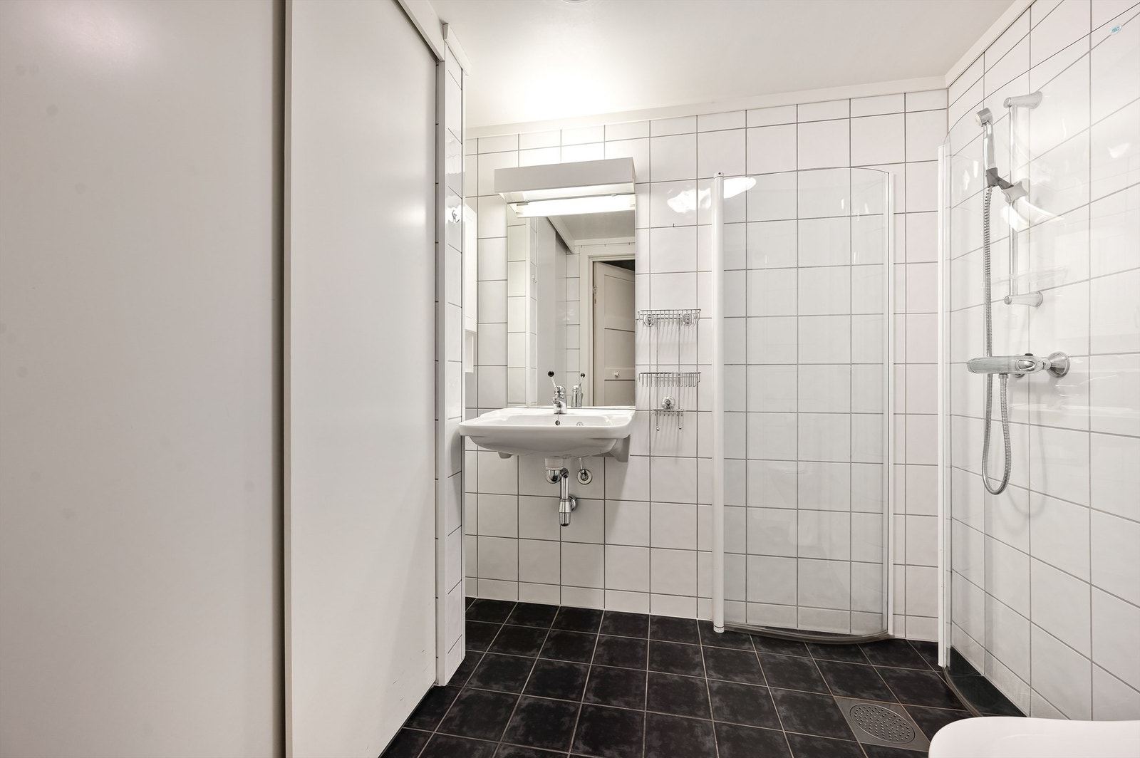 Flislagt bad med skyvedør foran vaskemaskin Galleribilde
