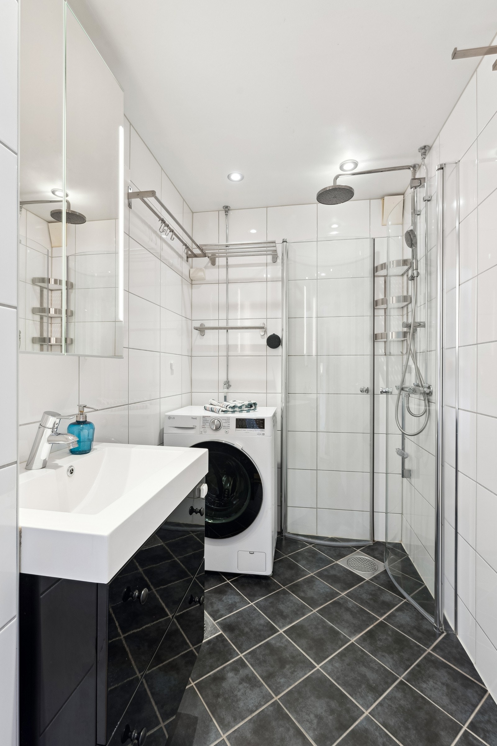 Flislagt baderom med varmekabler og består av servant med underskap, overskap med speilfronter, inn-/utadslående dusjdører og opplegg for vaskemaskin. Vaskemaskin medfølger. Galleribilde