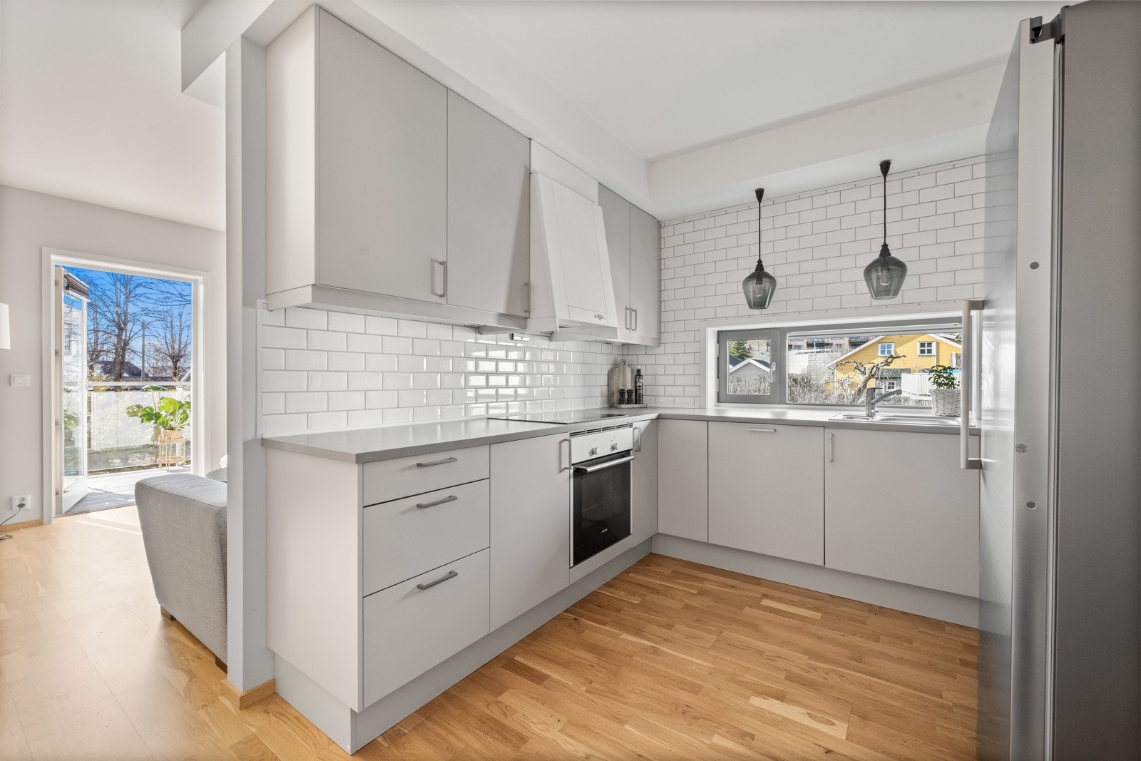 Innredningen har slette fronter, laminat benkeplate og fliser på veggen mellom benk og overskap. Galleribilde