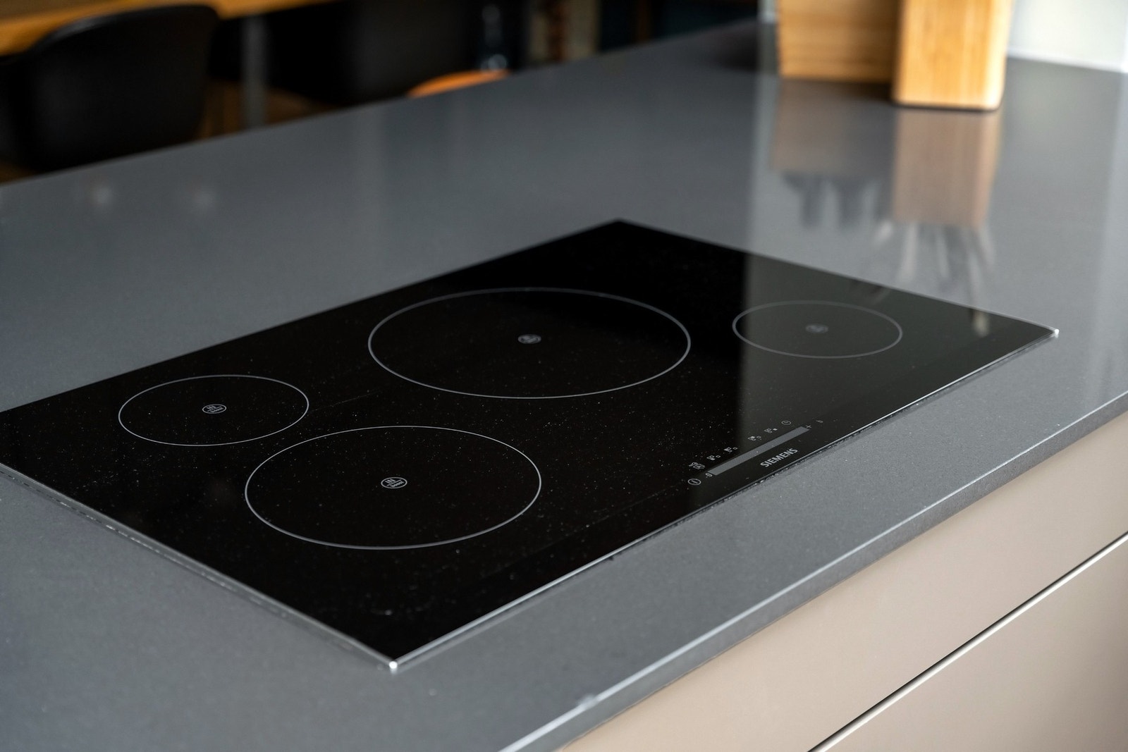 Nedfelt induksjonstopp fra Siemens i kjøkkenøy. Ventilatorvifte er takhengt. Galleribilde