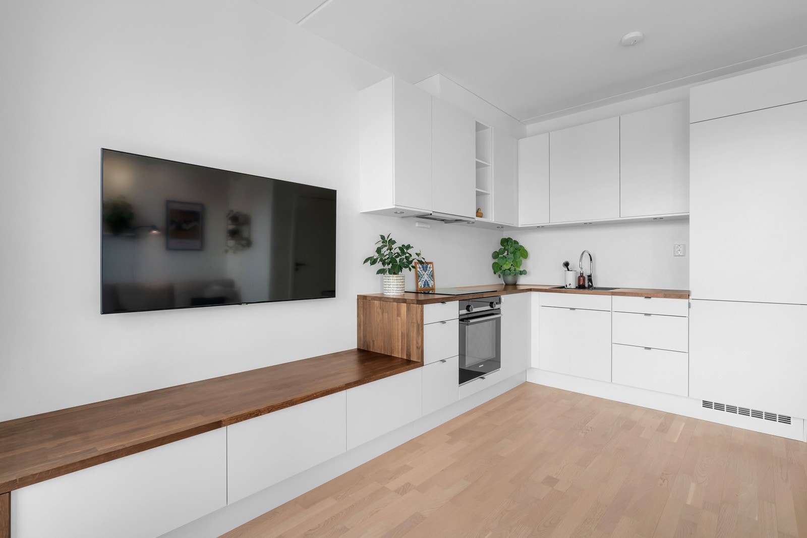 Leilighetens kjøkken er fra Sigdal og har integrerte hvitevarer i form av stekeovn, induksjonsplatetopp og kombiskap Galleribilde