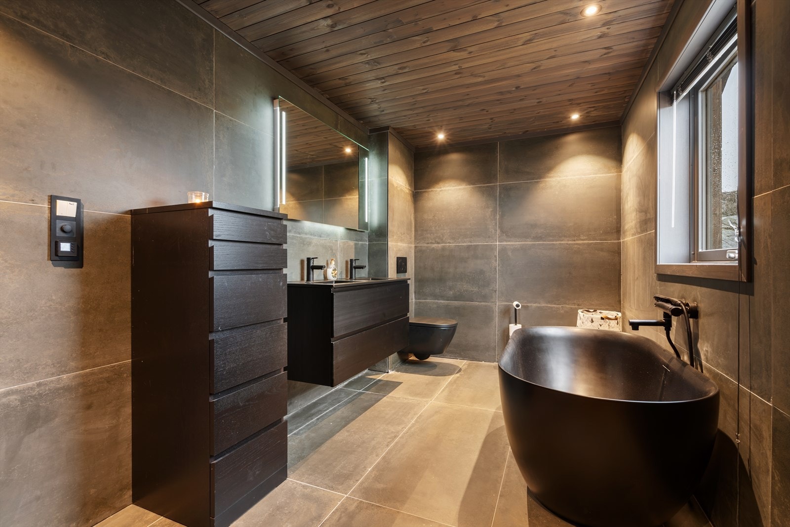 Stilfullt baderom med baderomsseksjon med 2 servanter, badekar, dusj og vegghengt toalett Galleribilde