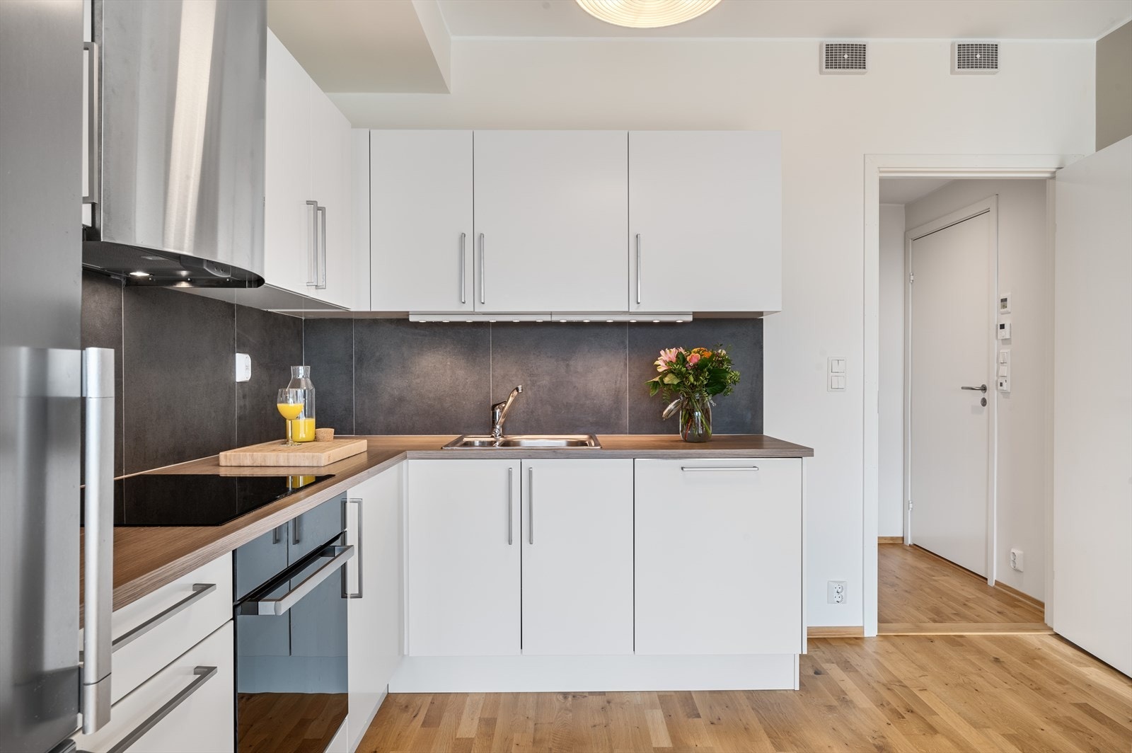 Kjøkkenet er lyst med glatte fronter og laminat benkeplate. Det er også lagt fliser i bakkant. Galleribilde