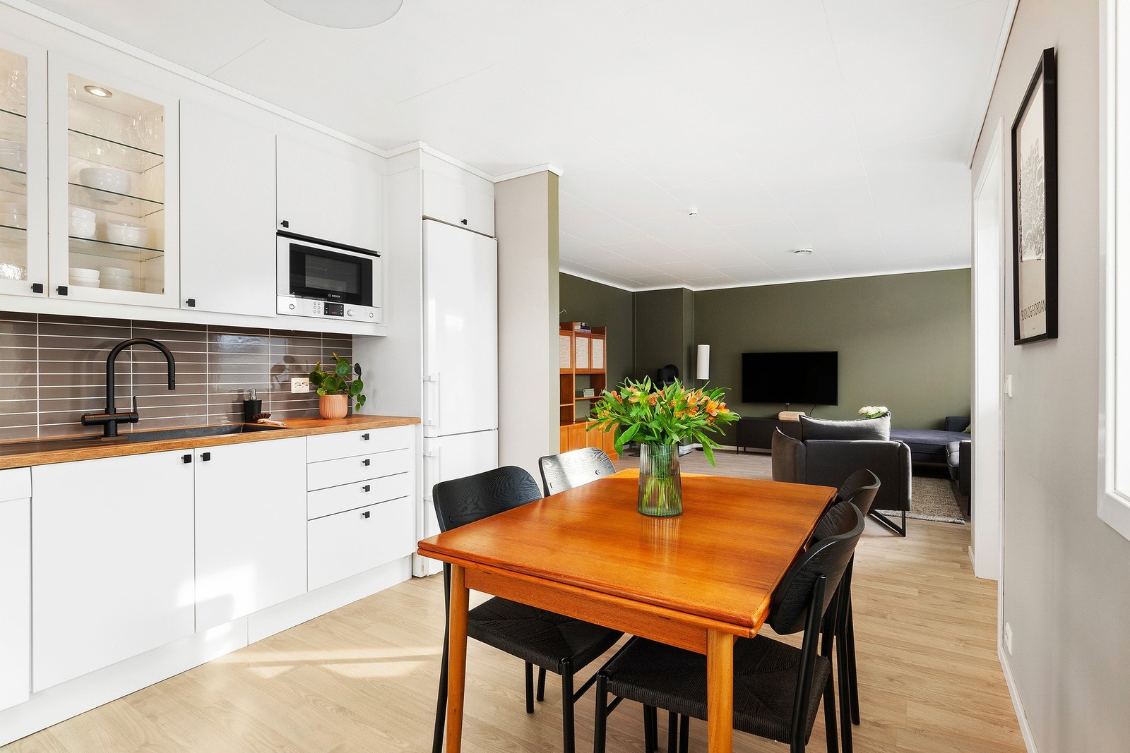 Stilren og takhøy innredning på kjøkken. Leiligheten har åpen løsning til stue. Legg merke til den flotte harmonien mellom gulv og de olivengrønne overflatene. Galleribilde