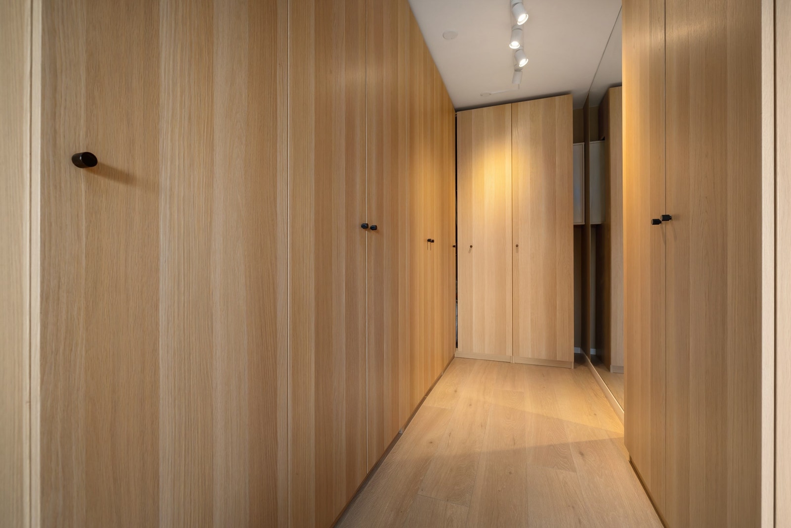 Denne lekre løsningen gir følelsen av et "walk-in closet" samtidig som det bugner av oppbevaringsplass! Galleribilde