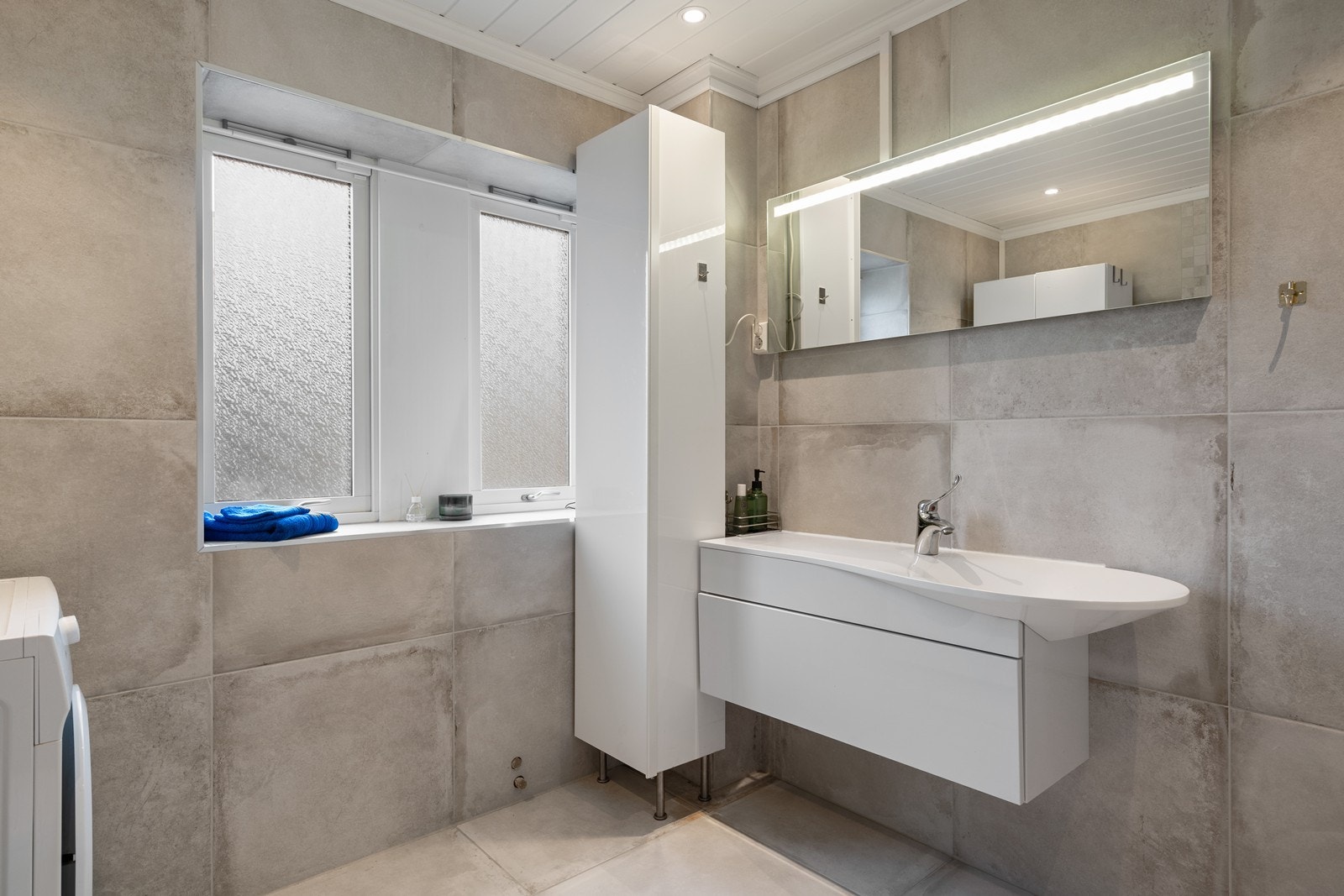 På badet er det store fliser på vegger og gulv og Innredning med bl.a. høyskap Galleribilde