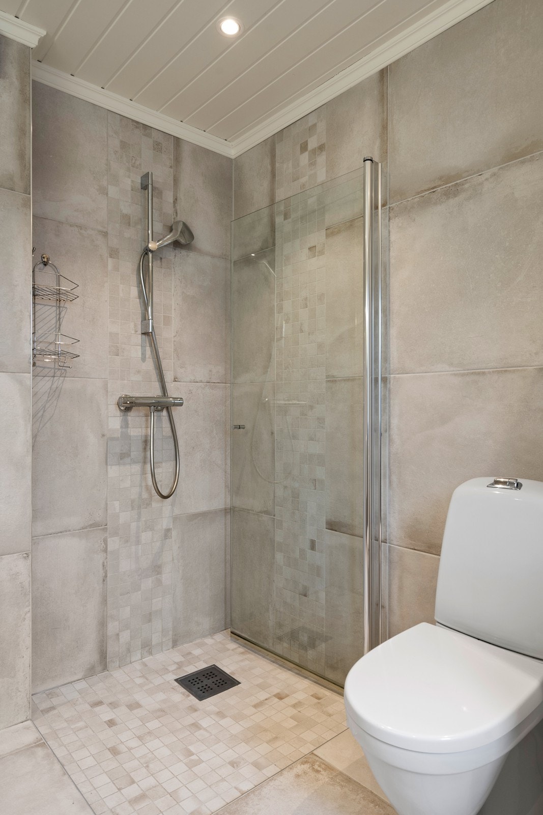 Dusjhjørne med glassdør og fine sjatteringer i flisene Galleribilde