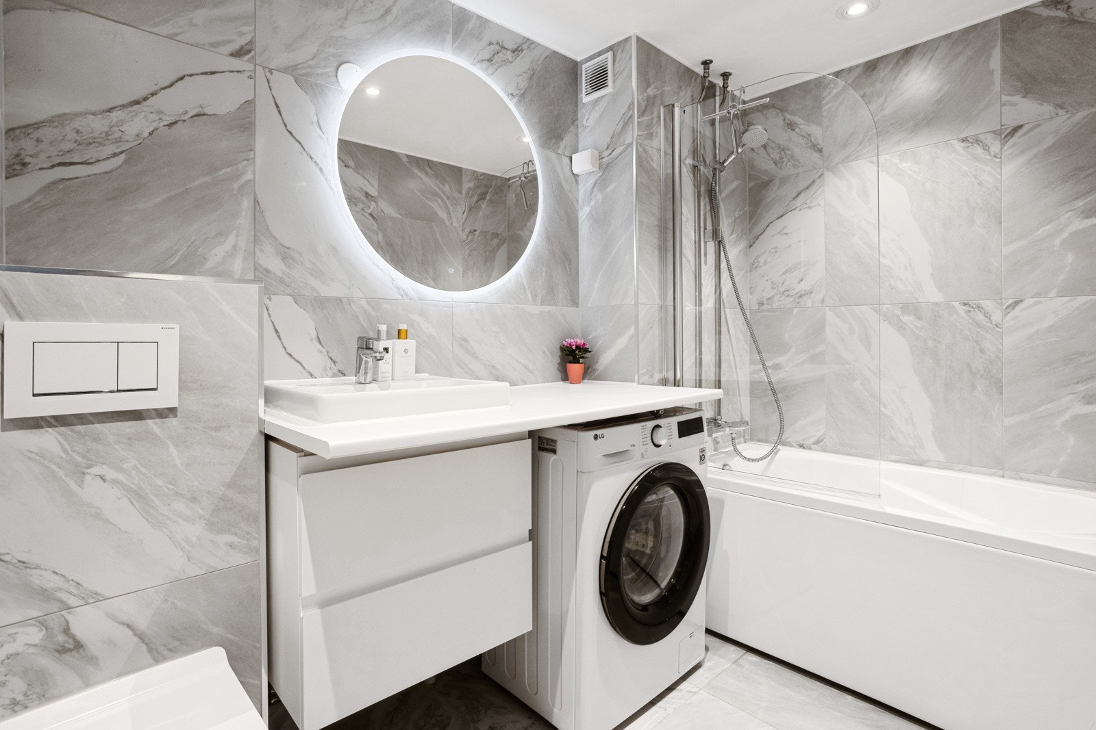 Et stilrent og funksjonelt baderom av god størrelse med opplegg til vaskemaskin. Galleribilde