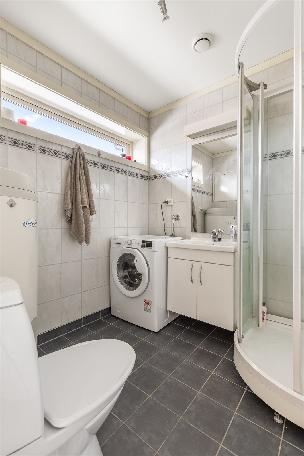 Badet er innredet med dusjkabinett, toalett, servant og har opplegg for vaskemaskin Galleribilde