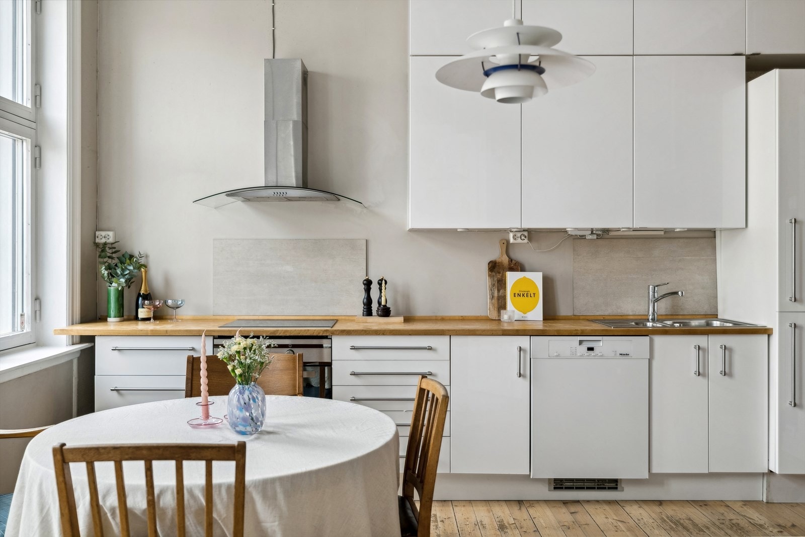 Ikea kjøkkeninnredning med slette folierte høyglansfronter, heltre benkeplate m/sprutplate over koketopp. Integrert koketopp, stekeovn og kjøl-/fryseskap, samt frittstående oppvaskmaskin. Galleribilde