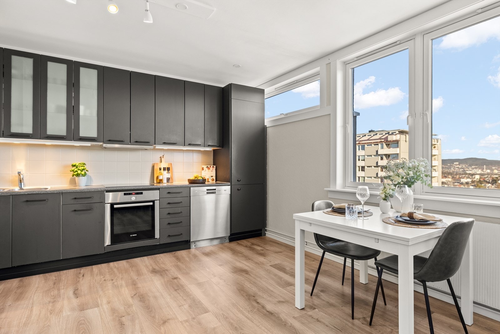 Pent, tidløst kjøkken med integrerte hvitevarer som kjøl/-fryseskap, platetopp og stekeovn. Frittstående oppvaskmaskin. Galleribilde