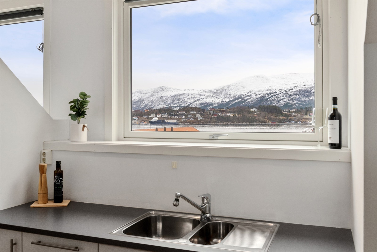 Store vindusflater gir fantastisk utsikt mot Aspevågen og sjøen, og slipper inn rikelig med naturlig lys, noe som gir en åpen og luftig atmosfære Galleribilde