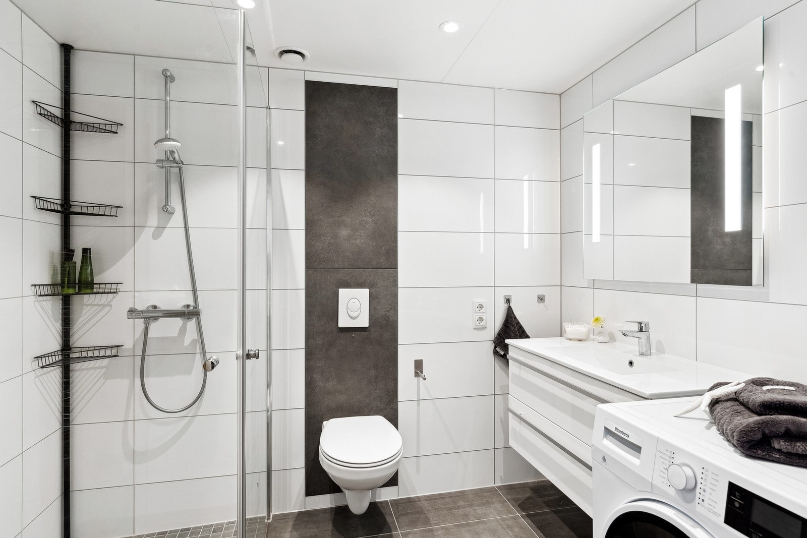 Lekkert bad med innfelbare dusjdører i herdet glass, vegghengt WC og speilbelysning. Galleribilde