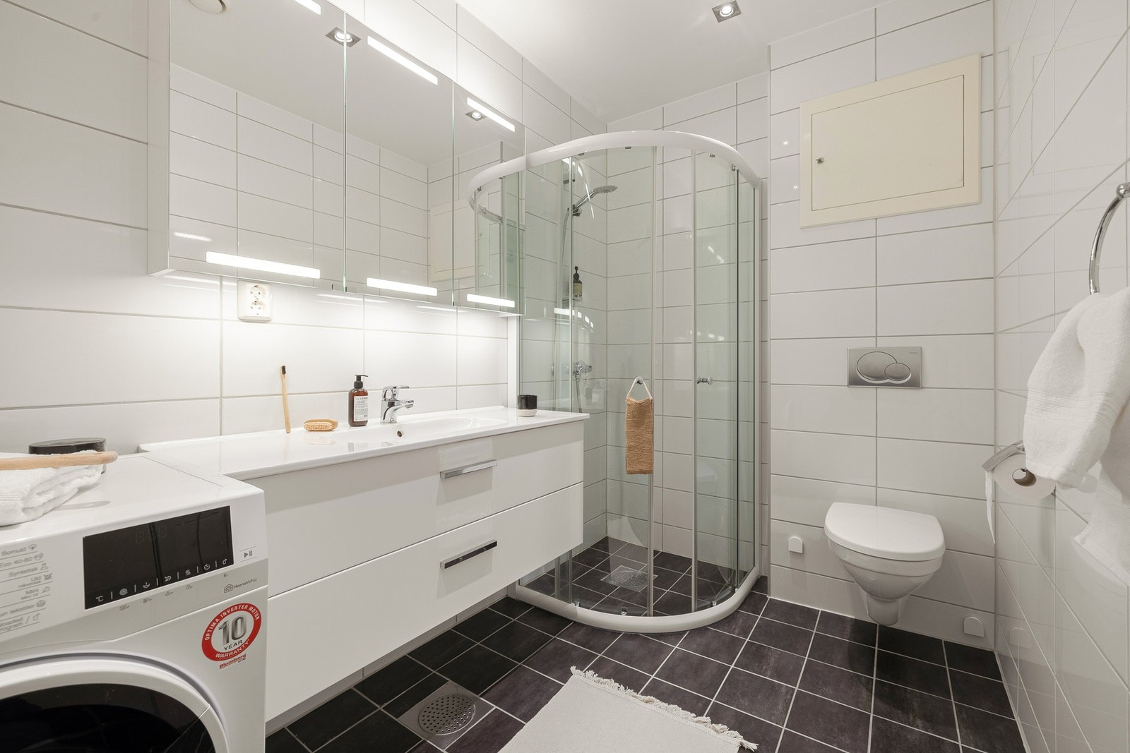 Badet er innredet med: Dusjkabinett, vegghengt toalett, opplegg for vaskemaskin og baderomsinnredning. Det er selvsagt varmekabler i gulv. Galleribilde