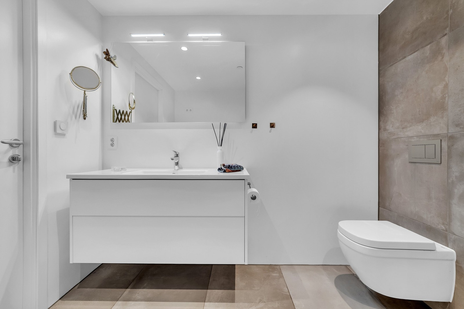 Badet har en gjennomført design med store, moderne fliser i nøytrale toner som gir et tidløst uttrykk. Galleribilde