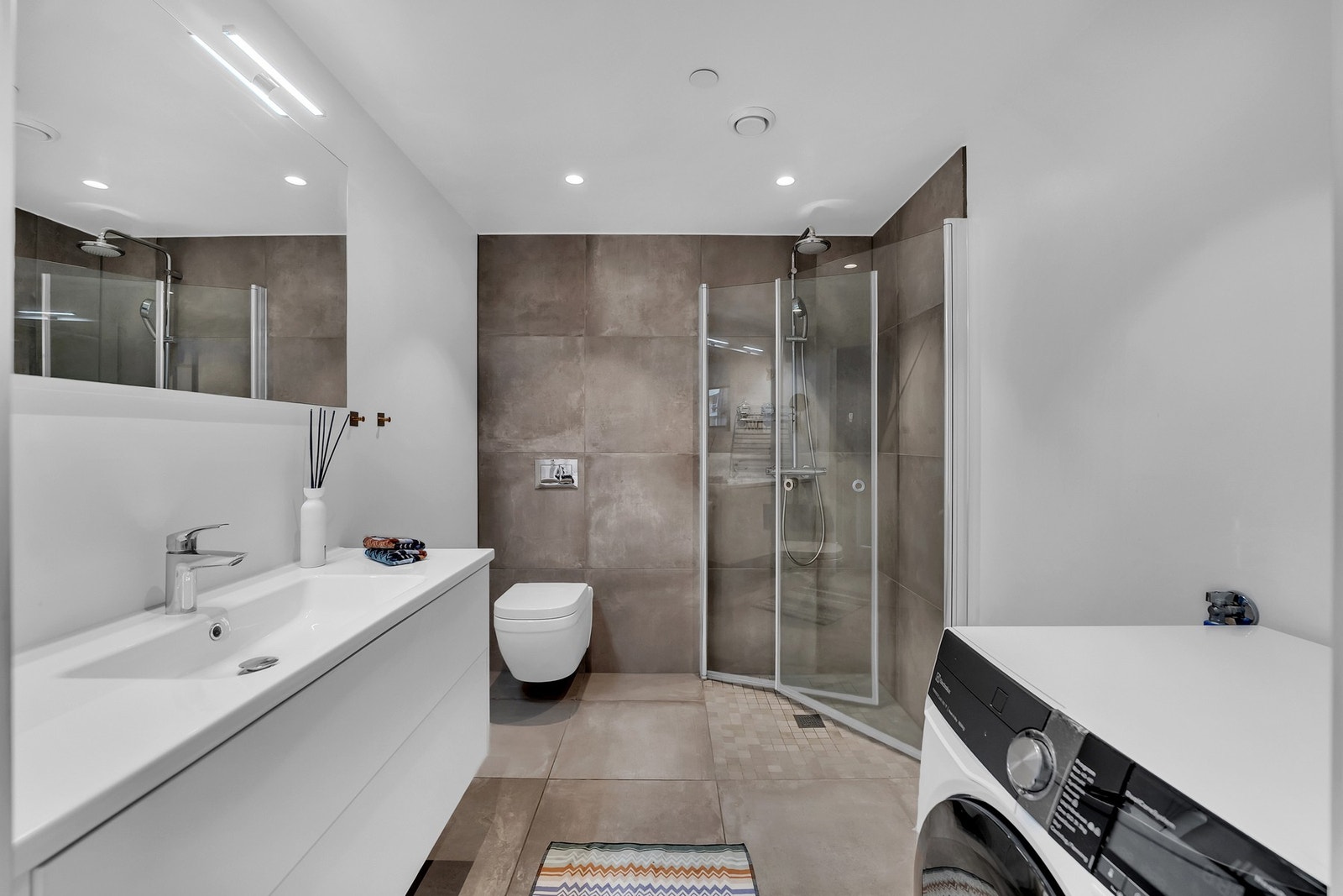 Dusjsonen med glassvegger skaper en eksklusiv følelse og gir en åpen romfølelse, samtidig som det er opplegg for vaskemaskin. Galleribilde