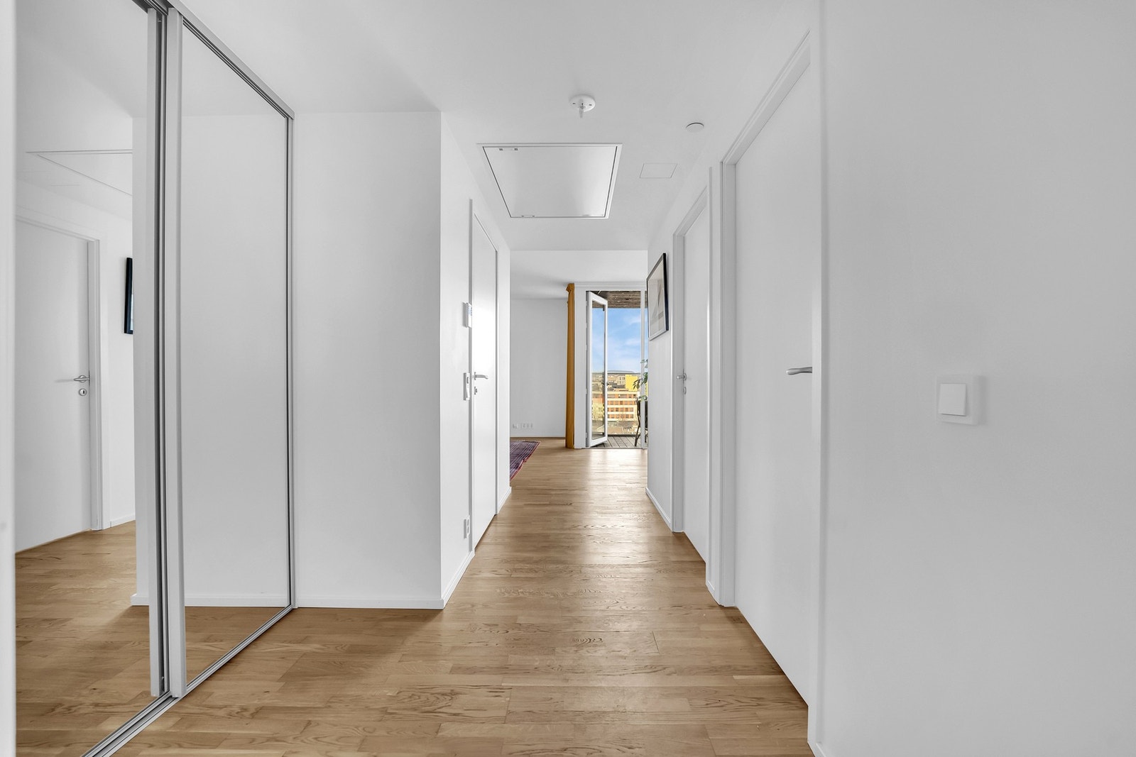 Gangen har en gjennomgående lys og moderne stil, med en praktisk skyvedørsgarderobe som gir en romslig følelse. Galleribilde