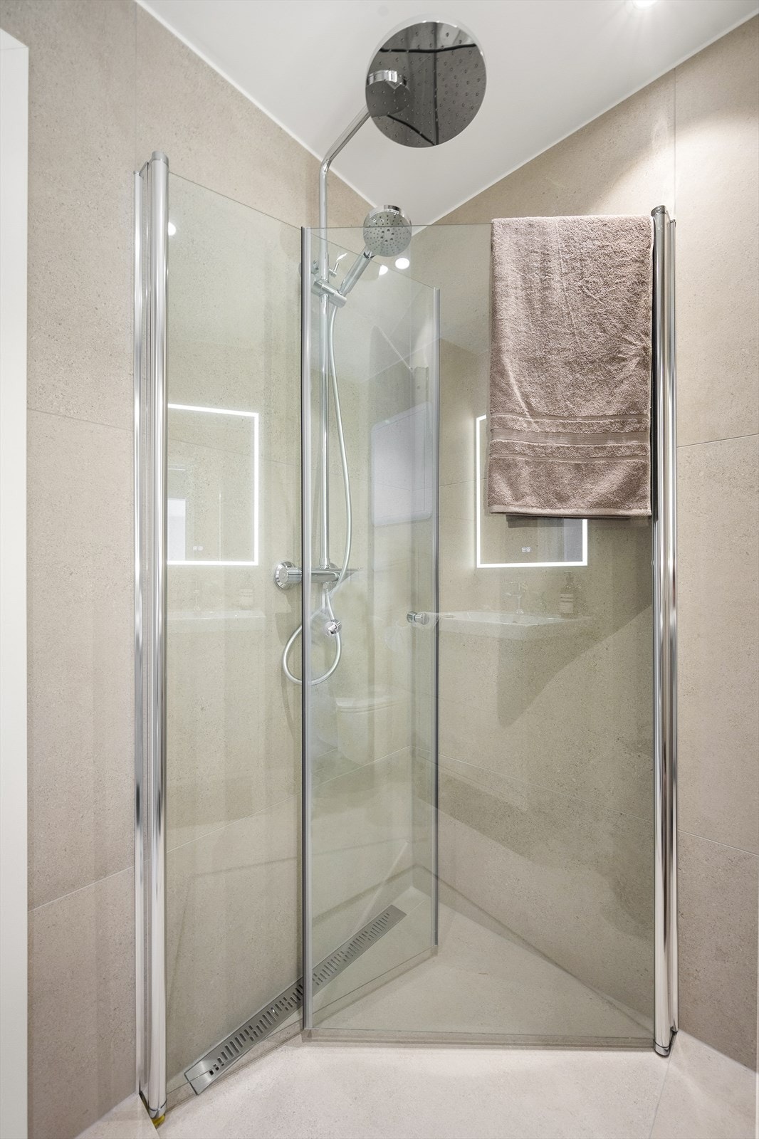 Badet har varmekabler i gulv, praktisk dusjhjørne, opplegg for vaskemaskin, vegghengt toalett og servant med innredning. Galleribilde