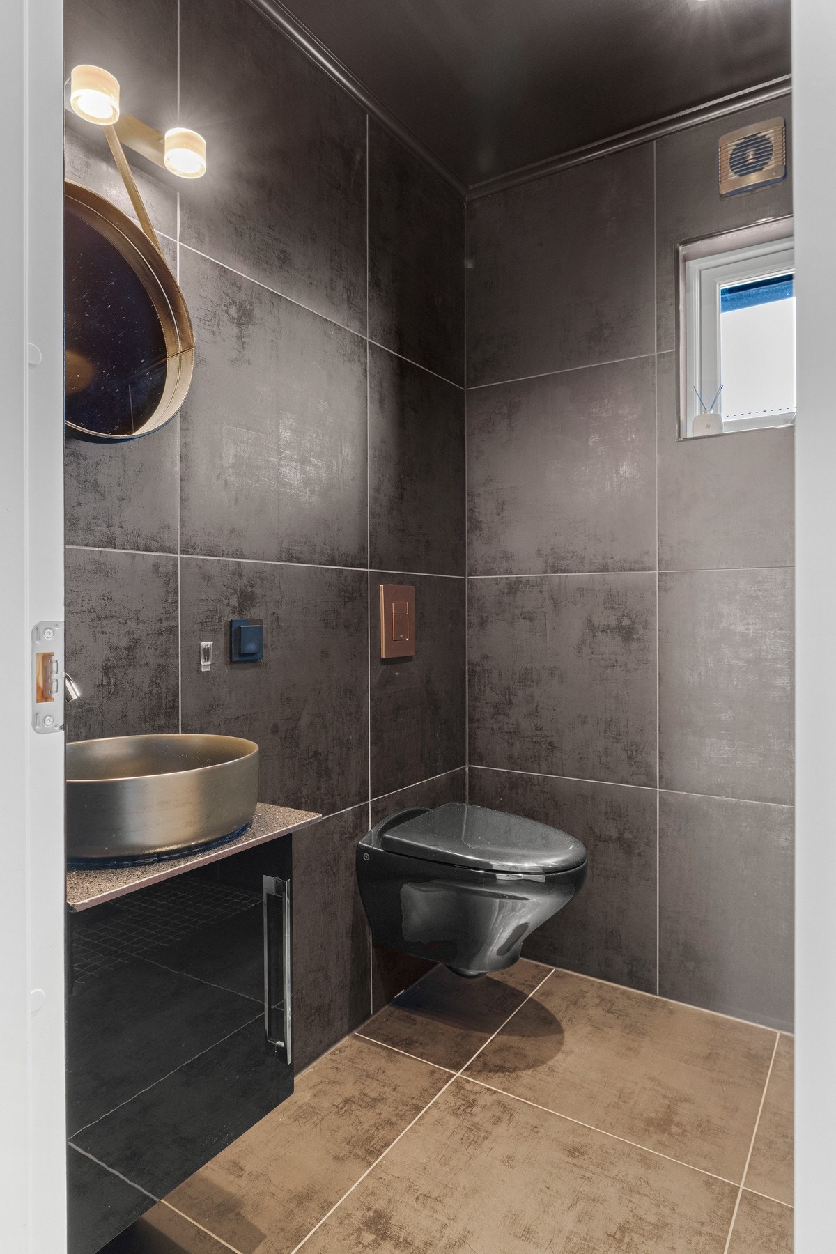 Det andre badet har et eksklusivt uttrykk, der store, mørke gulvfliser kombineres med sortmalt himling for en gjennomført atmosfære. Galleribilde